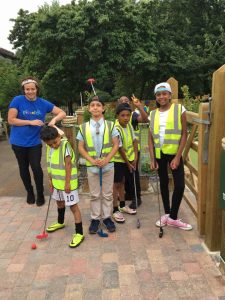 Kids wearing hi-vis jackets playing mini golf