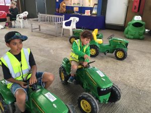 Kids sitting on two toy John Deere tractors